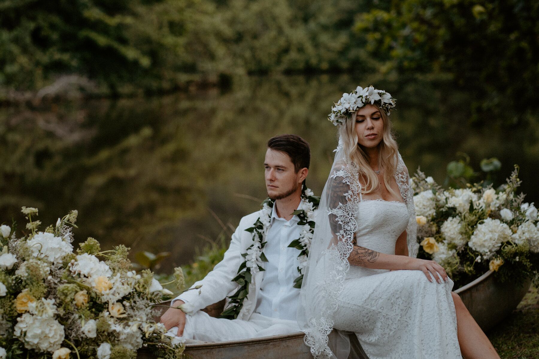 Newlyweds pose in floral filled canoe during their Oahu elopement.